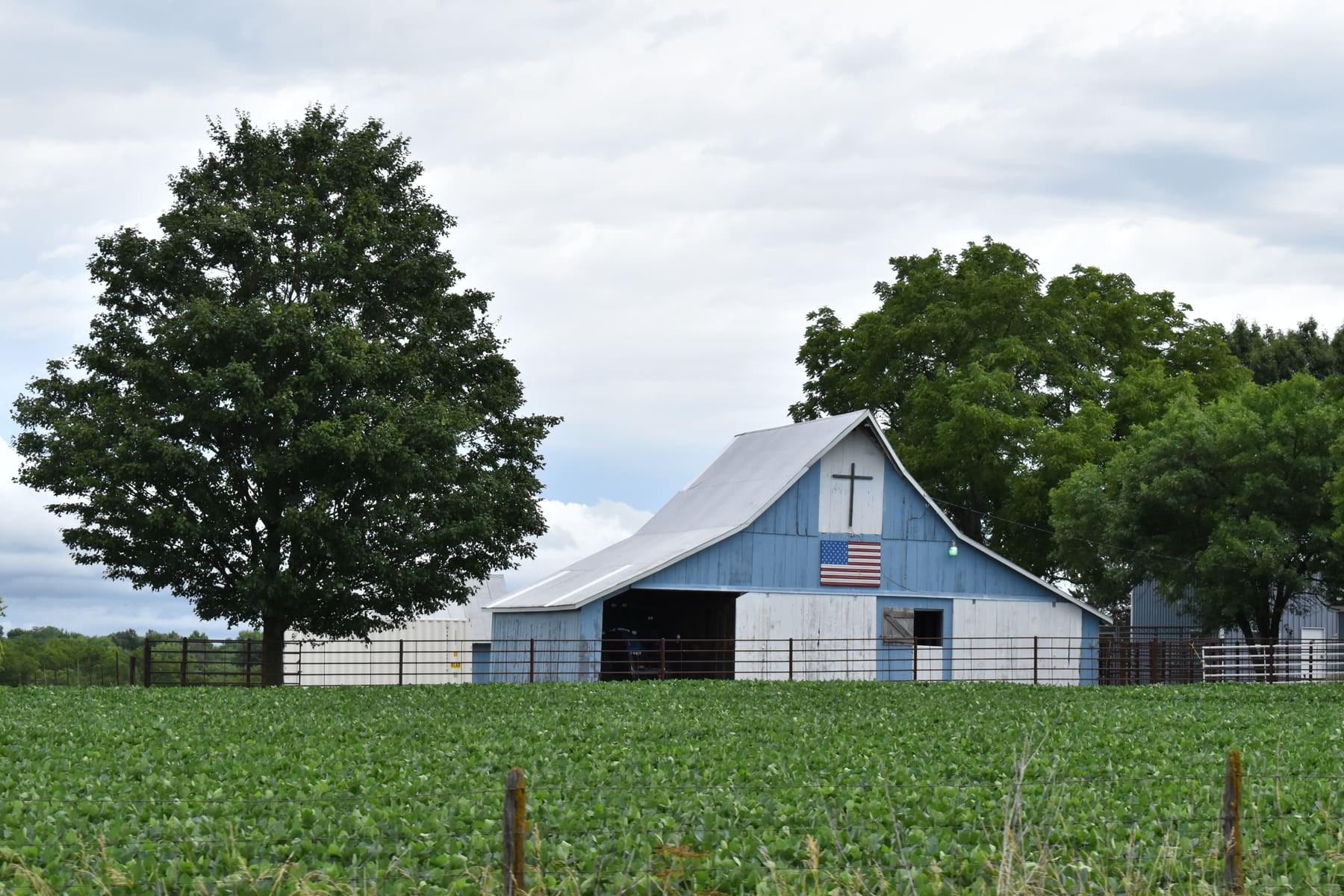 An American farm with a barn, cross, and flag