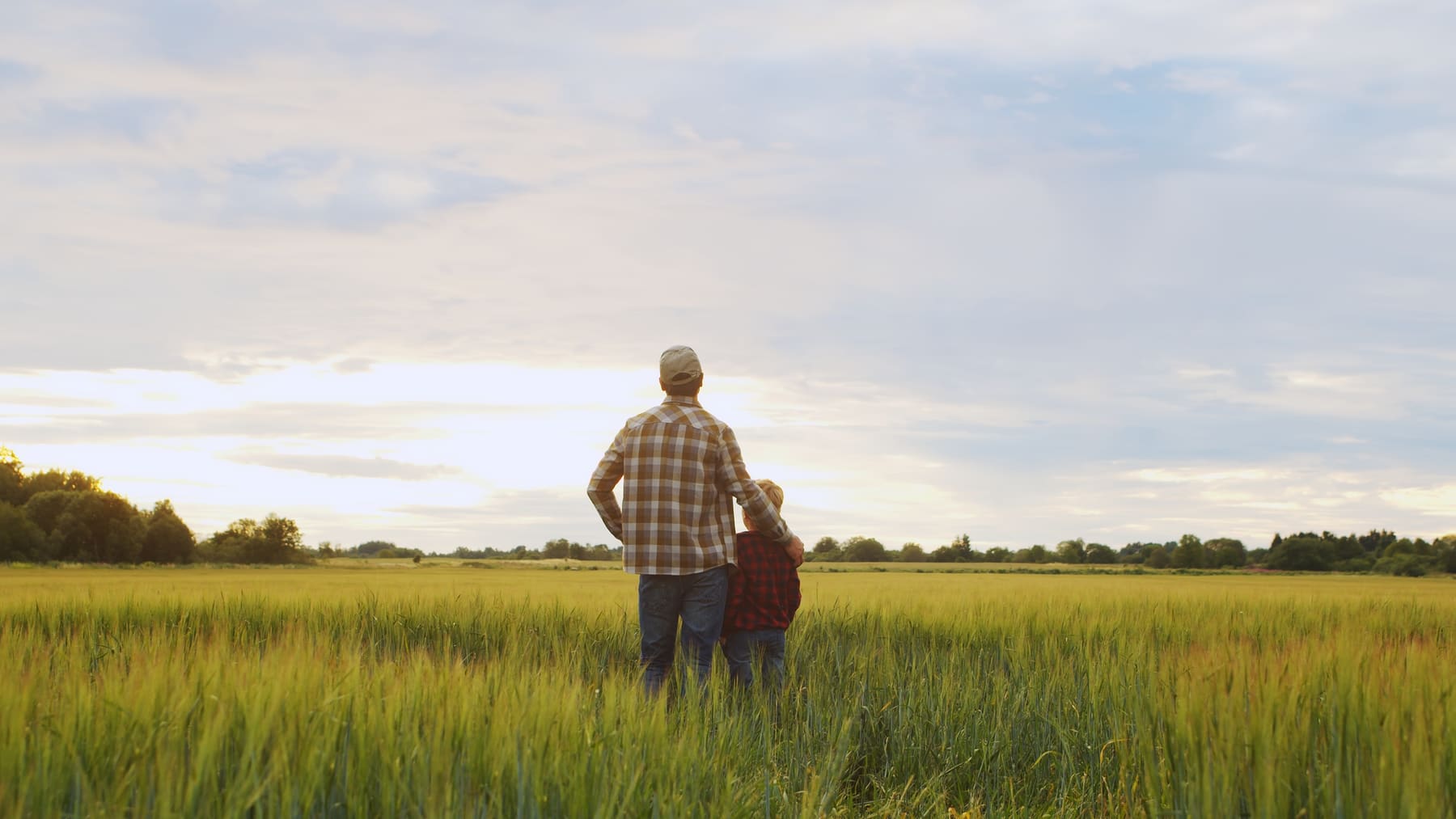 A farmer standing in a field with his child